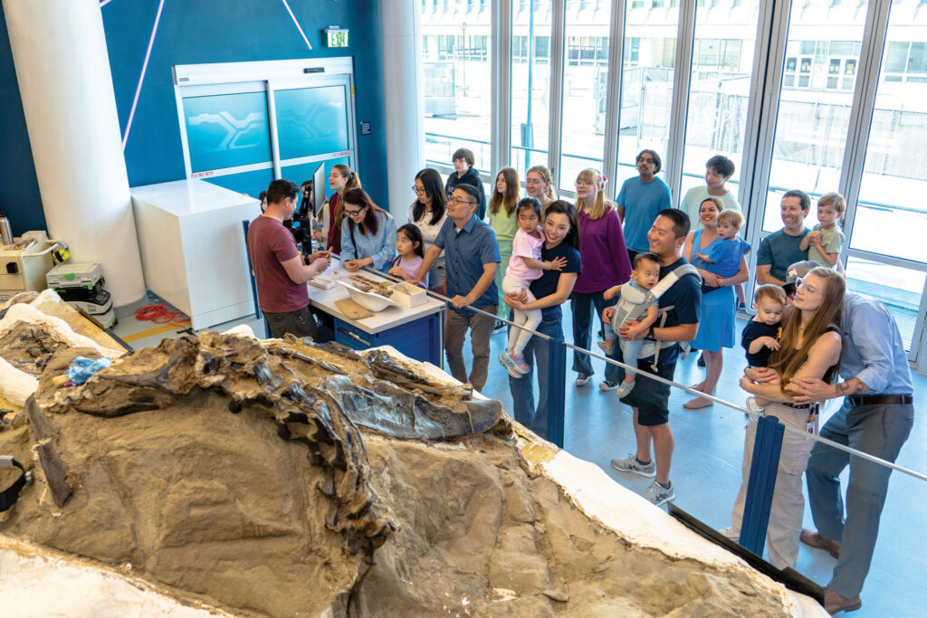 visitors engage with a paleontology expert in the museum's state-of-the-art lab